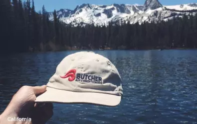 photo of a Butcher AC hat in front of icy mountains and a lake