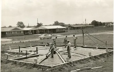 black and white photo of people constructing a home