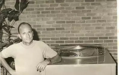 Black and white photo of a man next to an AC unit