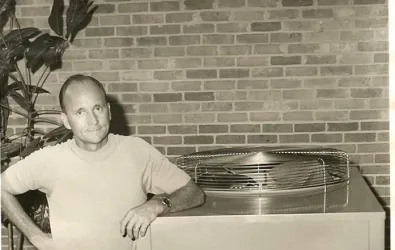 Black and white photo of a man next to an AC unit
