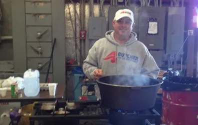 Butcher AC team member at company cookout with pot of food
