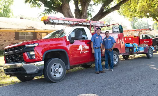 Image of two Butcher Air Conditioning technicians standing in front of a company truck on site of an AC installation job