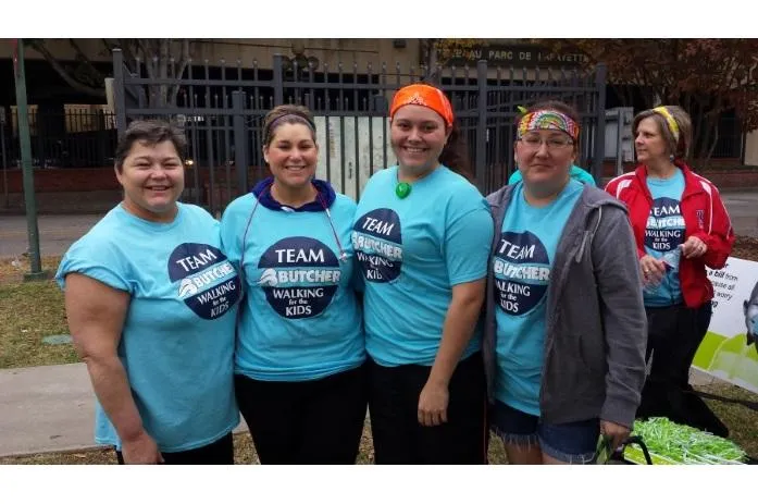 Five women in teal 'Team Butcher Walking for the Kids' shirts smiling outdoors at a charity walk