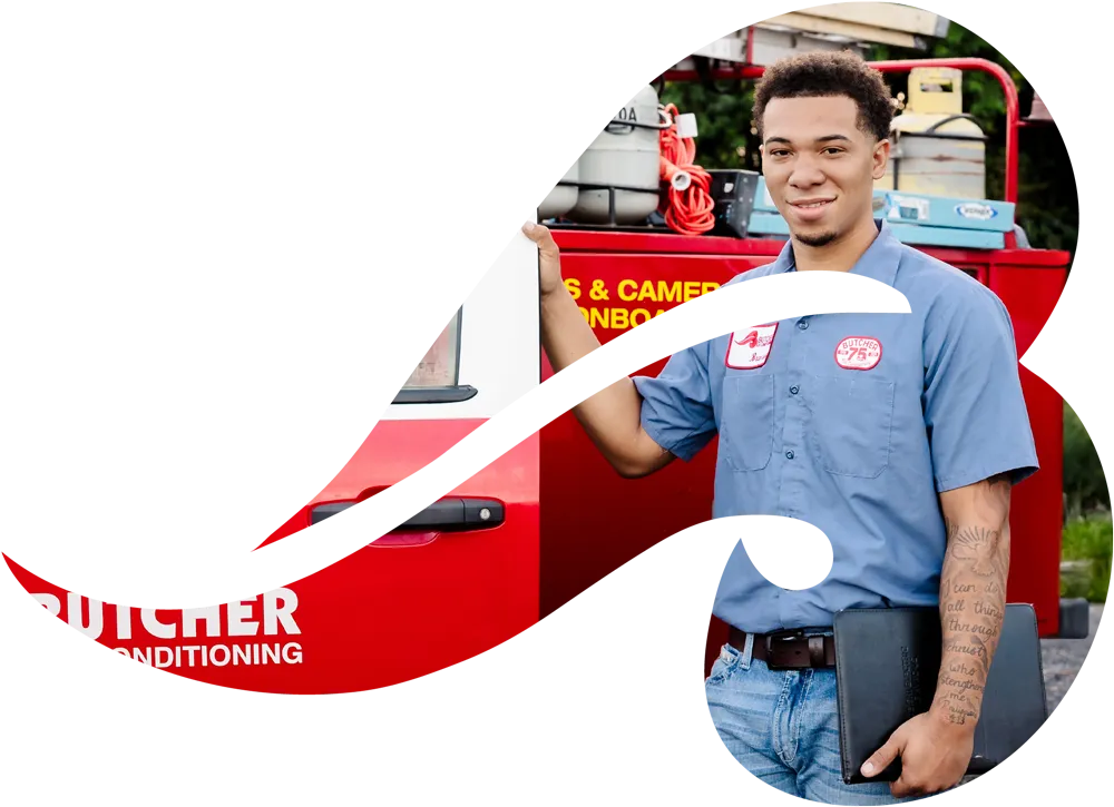 Smiling HVAC technician in blue uniform holding tablet by red service van with air conditioning equipment