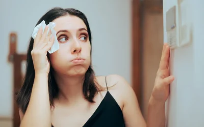 A woman checking her thermostat and dabbing her forehead during a Louisiana heatwave.