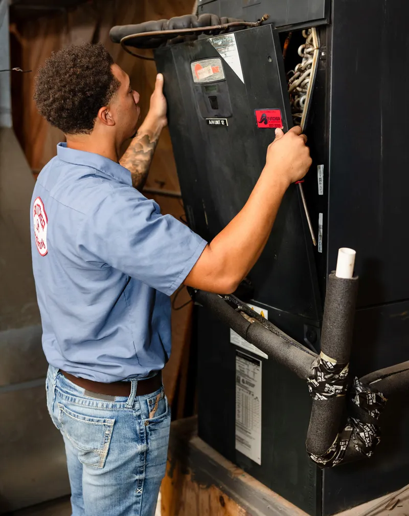 A man servicing a commercial HVAC air handler unit for maintenance and repair
