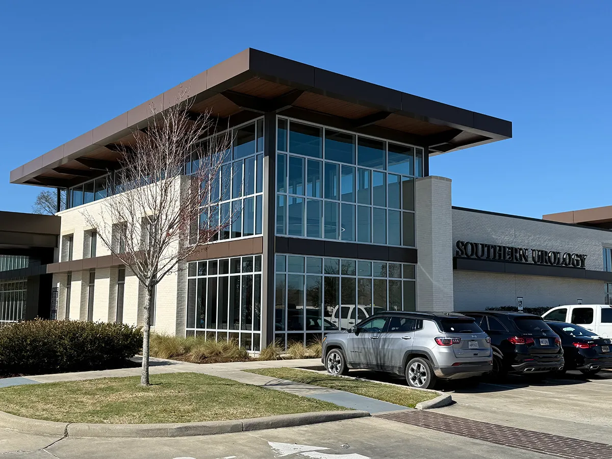 Southern Urology modern glass medical office building with parked cars and landscaped entrance under clear blue sky