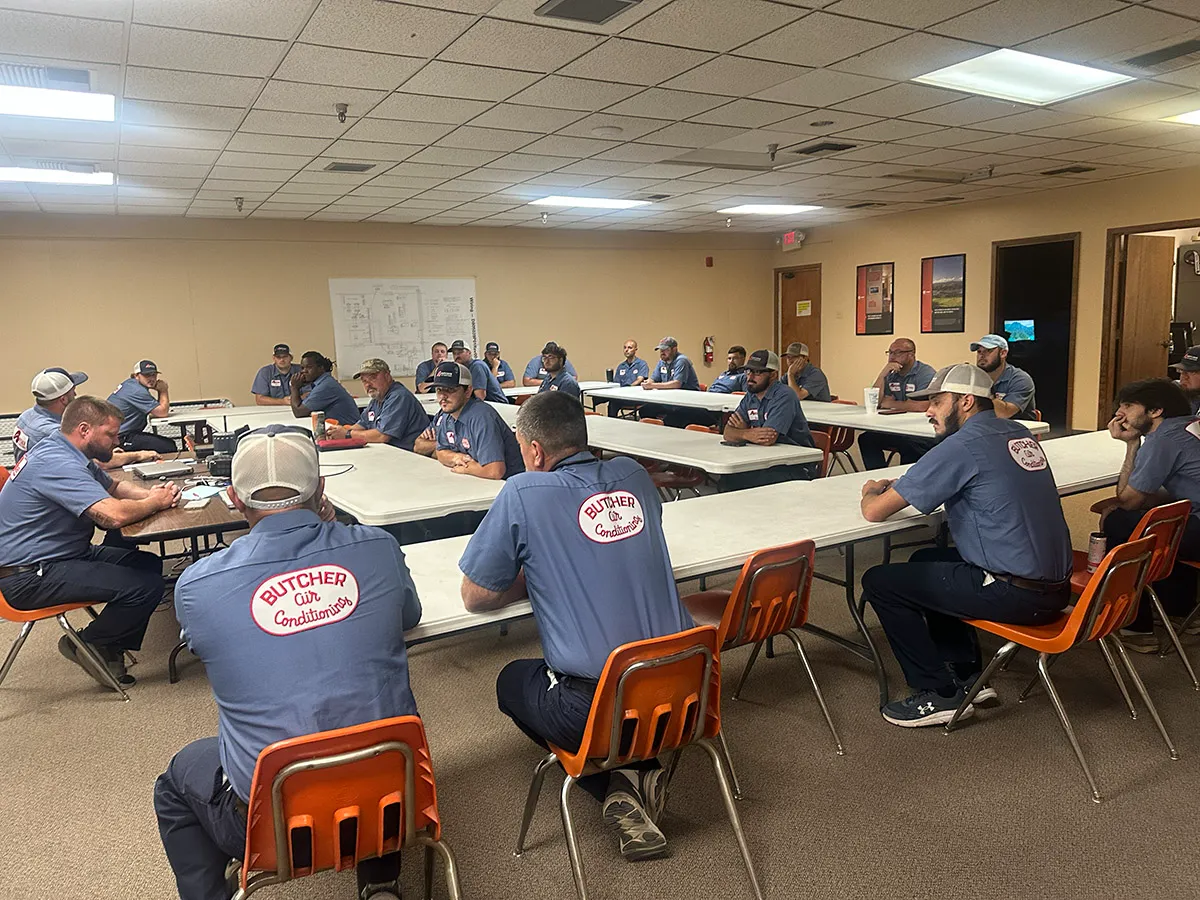 Group of men in Butcher Air Conditioning uniforms attending a training meeting in a company breakroom