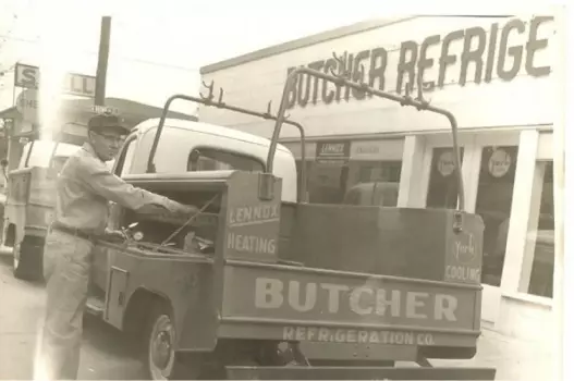 Vintage refrigeration service truck and a man technician loading tools outside Butcher Refrigeration shop