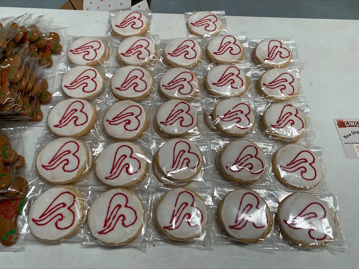 Individually wrapped round sugar cookies with white icing and red heart swirl, bakery display arranged in rows on table