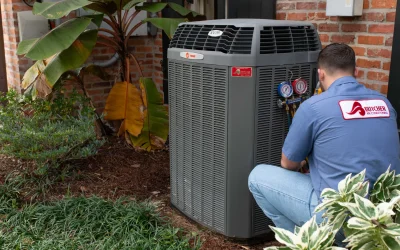 A man HVAC technician servicing outdoor air conditioning condenser unit with pressure gauges by a brick house
