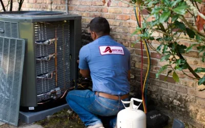 A man kneeling by outdoor air conditioner unit repairing HVAC system with refrigerant tank and manifold gauges.