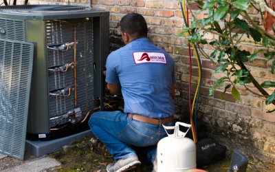 HVAC technician repairing outdoor air conditioner next to brick wall with refrigerant tank and service hoses