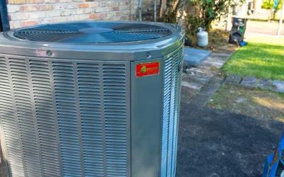 Close-up of outdoor central air conditioner condenser unit beside brick house, gray residential HVAC system