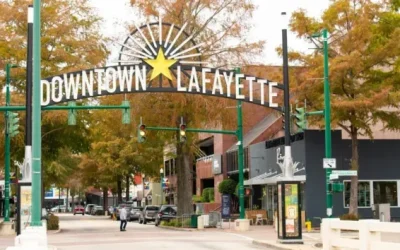 Downtown Lafayette arch sign over Main Street with fall foliage, shops, parked cars and pedestrians