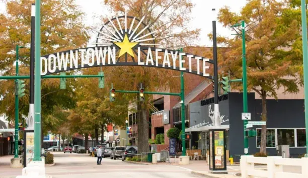 Downtown Lafayette arch sign over Main Street with fall foliage, shops, parked cars and pedestrians